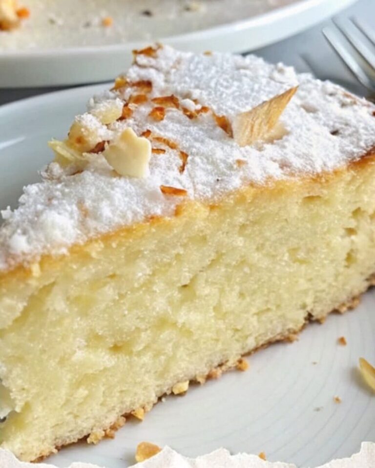 Fetta di torta chiara con zucchero a velo e mandorle in superficie